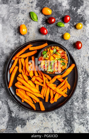 Des frites de patates douces et bol de trempette de basilic tomates Banque D'Images