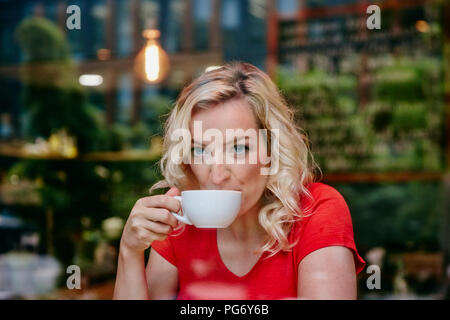 Portrait of blond woman drinking coffee in a cafe Banque D'Images