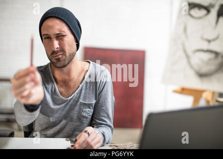 Artiste assis à son bureau en studio crayon contrôle Banque D'Images