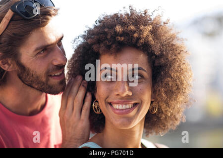 Happy young couple homme femme, chuchotant à l'oreille Banque D'Images