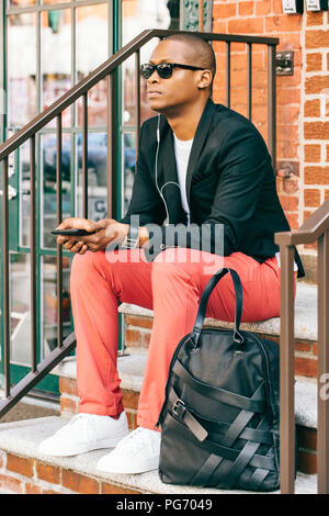 USA, NYC, Brooklyn, en attente de l'homme dans les escaliers, using smartphone Banque D'Images