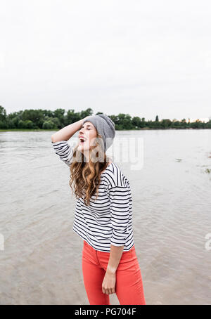Laughing woman wearing hat laineux à une rivière Banque D'Images