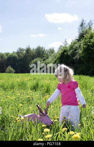 Petite fille avec lapin origami on meadow Banque D'Images