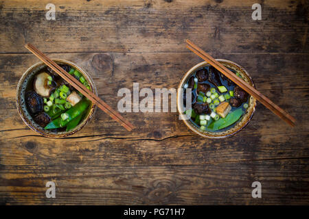 Deux bols de soupe miso japonais avec petits pois, champignons shiitake, le tofu et les graines germées Mung Banque D'Images