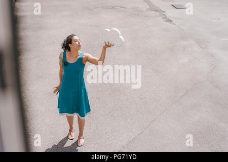 Femme debout dans la cour, holding, symbole nuage blowing kiss Banque D'Images