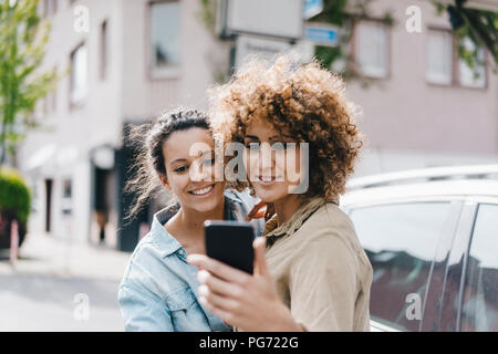 Meilleurs amis prendre des autoportraits avec un smartphone dans la ville Banque D'Images