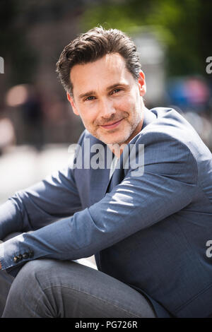 Portrait of smiling man sitting dans la ville Banque D'Images