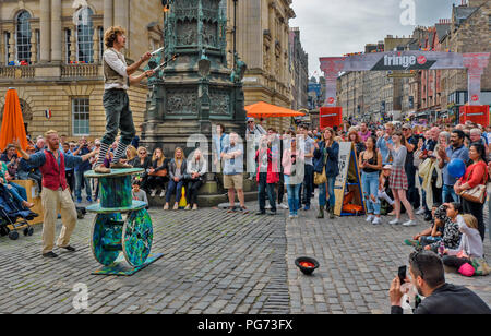 EDINBURGH FESTIVAL FRINGE 2018 FIRE JUGGLER en équilibre sur de grandes bobines en bois Banque D'Images