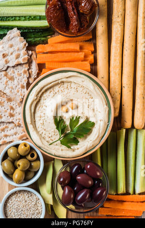 Vue de dessus de l'humus dans le bol avec les légumes coupés en tranches, bâtonnets, olives et pain pita Banque D'Images