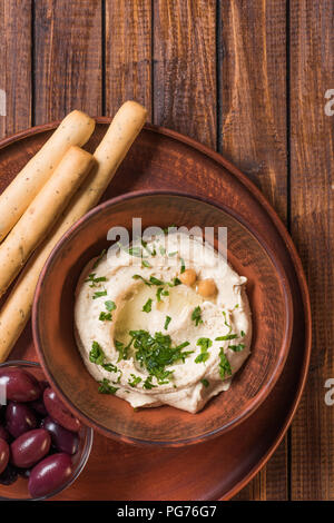 Vue de dessus d'olives, de l'hummus et gressins de persil et les pois chiches dans un bol sur la surface en bois Banque D'Images