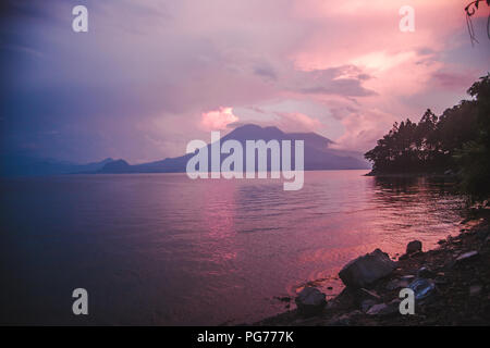 Rose et violet coucher du soleil avec vue sur un volcan sur le lac Atitlan, Guatemala Banque D'Images