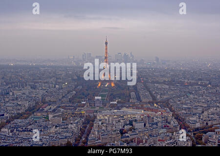 Vue aérienne sur la Tour Eiffel et le parc du Champ-de-Mars, avec des gratte-ciel du quartier d'affaires de la Défense en arrière-plan, à l'aube. Paris, France Banque D'Images