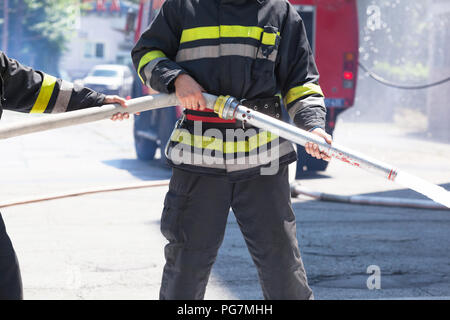 Les pompiers en action, d'éteindre le feu avec le tuyau d'incendie Banque D'Images