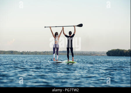 Couple holding une pagaie en étant debout sur un surf Concept lifestyle, sport, de l'amour Banque D'Images