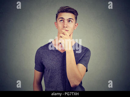 Young man looking up contemplant sur les plans d'avenir a des doutes Banque D'Images