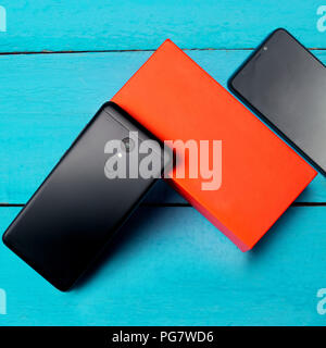 Deux smartphones sur le dessus d'une planche de bois, sur fond bleu et orange box Banque D'Images