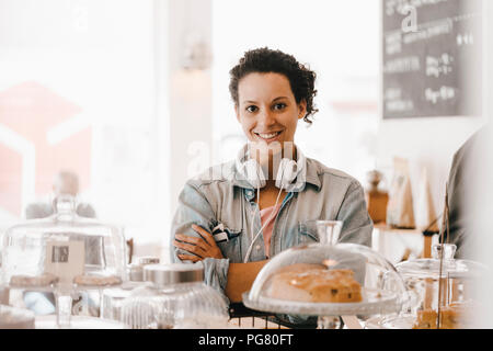 Woman standing in coffee shop with arms crossed Banque D'Images