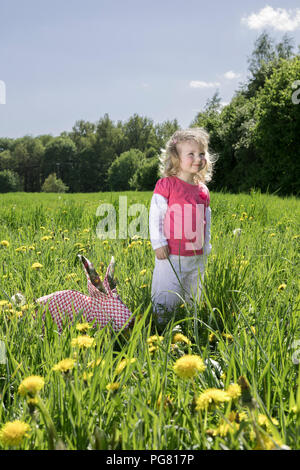 Petite fille avec lapin origami on meadow Banque D'Images