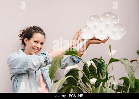 Smiling woman holding nuage au-dessus de plante Banque D'Images