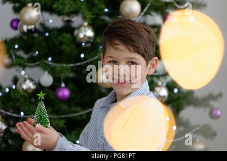 Portrait of smiling little boy avec l'arbre de Noël miniature Banque D'Images
