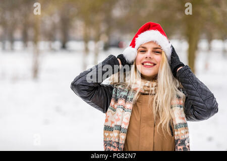 Portrait of smiling blonde woman wearing Christmas cap en hiver Banque D'Images