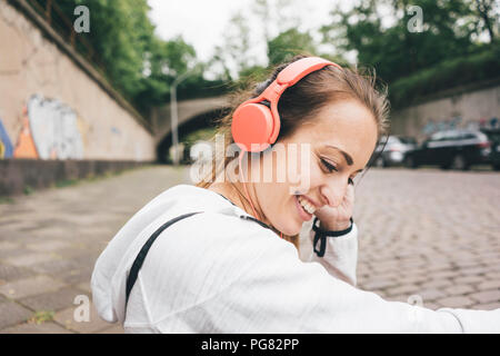 Sportive Smiling young woman wearing headphones outdoors Banque D'Images