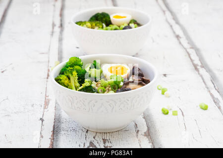 Deux bols de soupe de Ramen avec des œufs, du brocoli, des nouilles, des champignons shiitake et oignons de printemps Banque D'Images