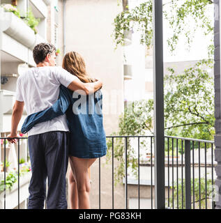 Vue arrière du couple dans des chemises de nuit debout sur balcon hugging Banque D'Images