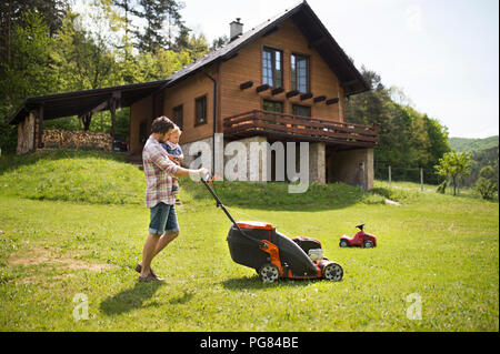 Père avec son petit fils de tondre la pelouse Banque D'Images