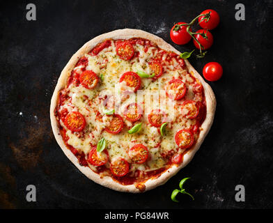 Pizza Margherita et tomates cerises sur la masse sombre Banque D'Images