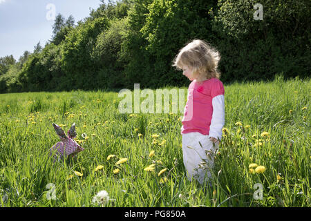 Petite fille avec lapin origami on meadow Banque D'Images