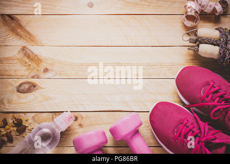Beauté et Soins du corps, du poids et de suivre un régime de vie sain concept. Les équipements de sport, des haltères, des chaussures de course, les cordes à sauter sur fond de bois. Banque D'Images