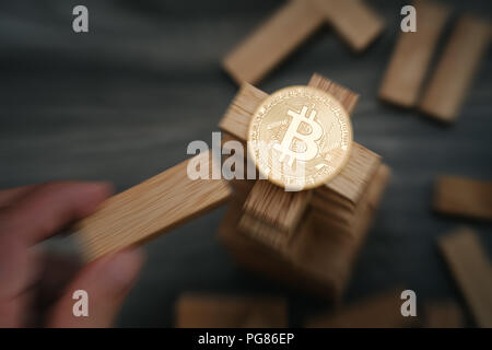 Sur le Bitcoin blocs de construction en bois de la tour part le déplacement d'un bloc. Effet de flou de zoom. Notion de risque bitcoin. Banque D'Images