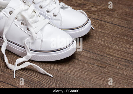 Baskets blanc sur la surface en bois sombre. Chaussures pour femmes en sport fashion style. Copy space Banque D'Images