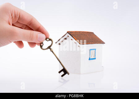 Main tenant une clé d'or près d'une maison sur un fond blanc Banque D'Images