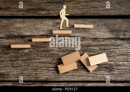 Découpes Silhouette d'un homme à monter des marches de bois avec des dominos plus ancien en bois rugueux la surface de la table. Banque D'Images