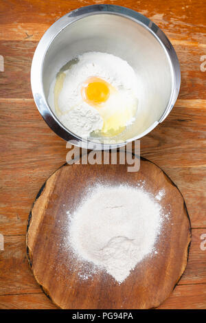 La cuisson de la tarte - tas de farine à bord et la farine avec les oeufs cassés dans un bol en acier Banque D'Images