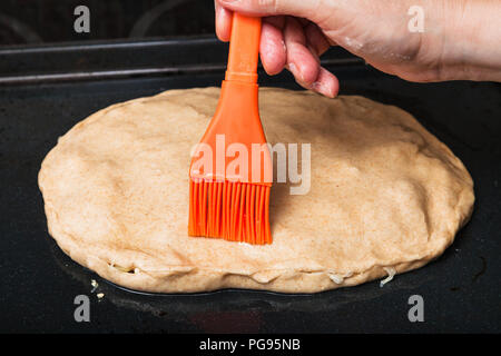 La cuisson de la tarte - huilage de la tarte crue par pinceau en silicone Banque D'Images