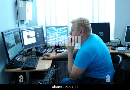 Ingénieur vidéo montage vidéo assis en face de moniteurs à l'agence de presse studio. Le 10 août 2018. Kiev, Ukraine Banque D'Images