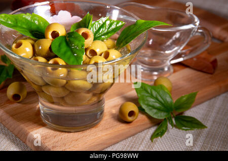 Green olives dénoyautées dans une tasse en verre avec de l'huile d'olive Banque D'Images