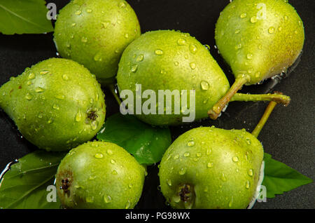 Poires vertes sur fond sombre saupoudré avec de l'eau close-up Banque D'Images