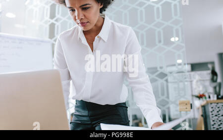 Jeune femme travaillant sur ordinateur portable. Busy businesswoman working on laptop in office moderne. Banque D'Images