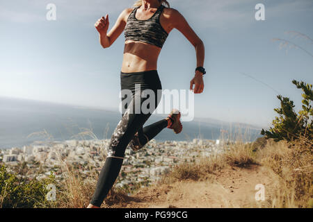 sportive sprint sur une piste rocheuse. Femme courant en descente sur le sentier de montagne. Banque D'Images