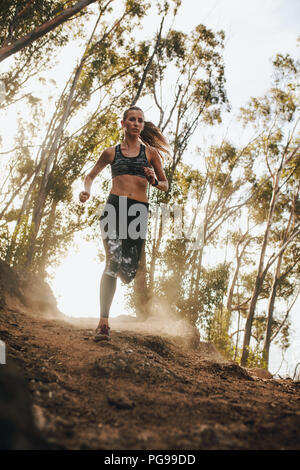 Toute la longueur de course femme fitness sur sentier de montagne. Coureuse d'exécution sur un sentier de montagne rocheuse. Banque D'Images