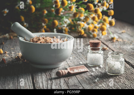 Mortier d'herbes médicinales séchées, globules homéopathiques et tas de plantes de camomille. L'homéopathie et la phytothérapie. Banque D'Images