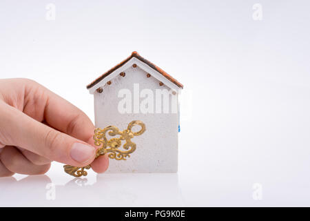 Main tenant une clé d'or près d'une maison sur un fond blanc Banque D'Images