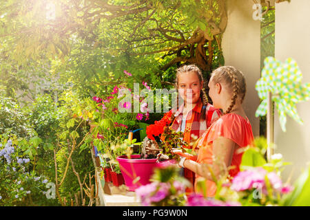 Deux belles filles la plantation dans des pots de géranium Banque D'Images