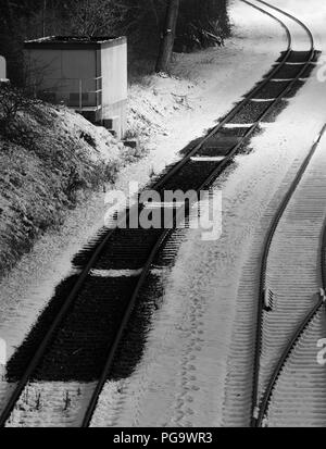 Empreintes laissées par wagons stationnés au cours de neige. Noir et blanc photo de nuit. Banque D'Images