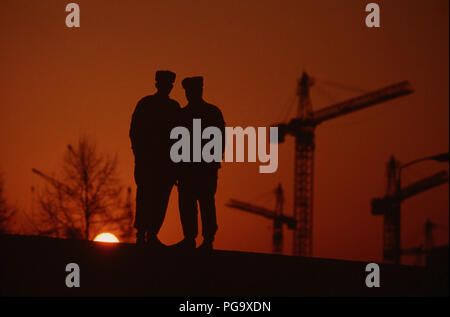 Mur de Berlin 1989 - stand des policiers est-allemands au sommet d'une section du mur de Berlin au coucher du soleil. Banque D'Images