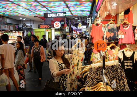 Une femme boutiques pour une robe sur le marché. Populaire avec les habitants et les touristes, Bugis Street Market est bien connu pour être l'un des endroits les moins chers à Singapour pour acheter des souvenirs, d'accessoires, vêtements, appareils électroniques, articles ménagers et des produits cosmétiques. Banque D'Images